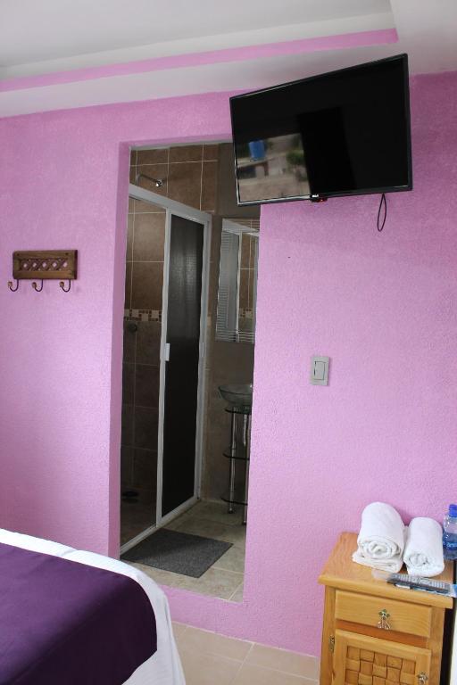 1 dormitorio con pared de color rosa y espejo en Hotel Boutique Tonalli, en San Martín de las Pirámides