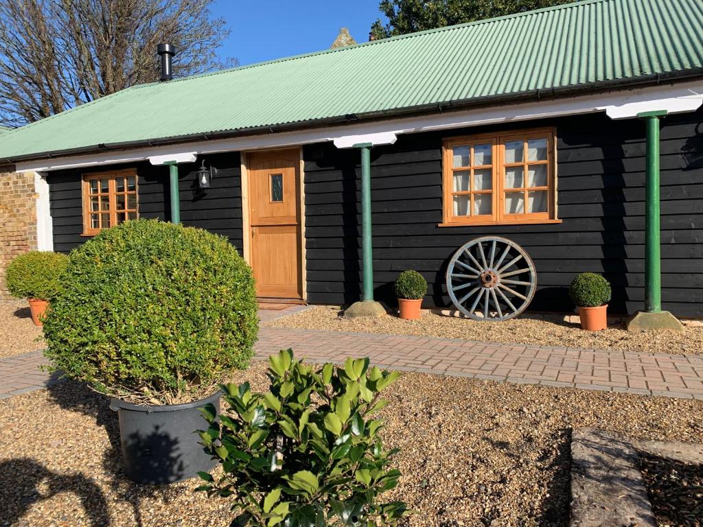 a black building with a wheel in front of it at Cheesemans Farm Stables in Manston