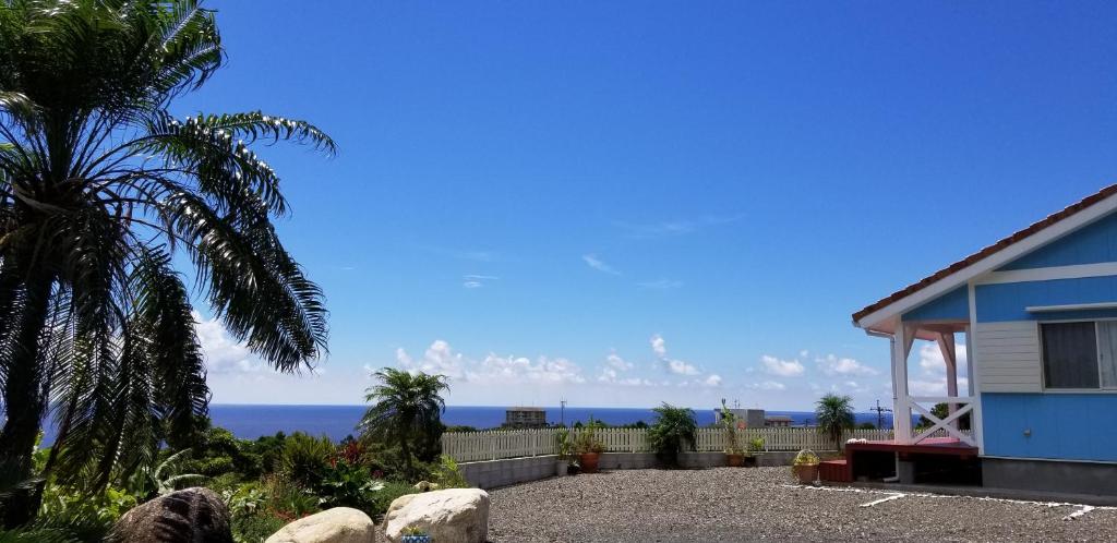 a blue house with the ocean in the background at Yakushima Pension Luana House in Yakushima