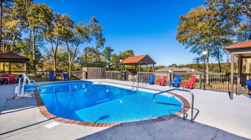 a swimming pool at a park with chairs and trees at Motel 6-Hot Springs, AR in Hot Springs