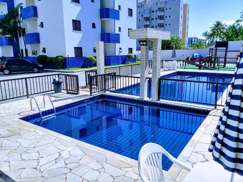 a pool at a hotel with two chairs and a building at Ed.fragatas residence in Bertioga