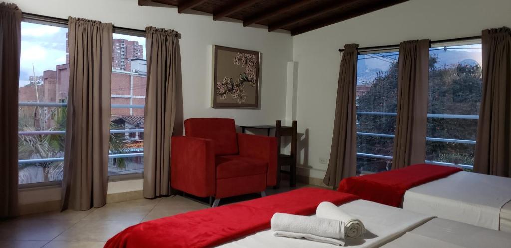 um quarto com uma cadeira vermelha, uma cama e uma janela em Gemas San Joaquin 1 em Medellín