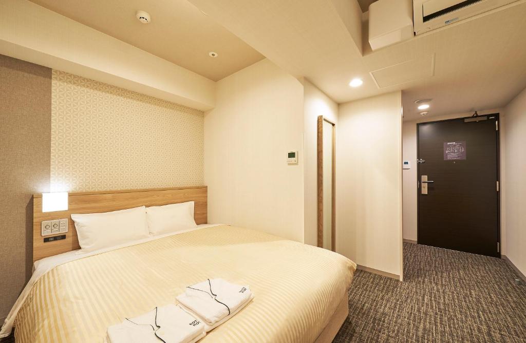 a hotel room with a bed and a door at Sotetsu Fresa Inn Nagoya Sakuradoriguchi in Nagoya