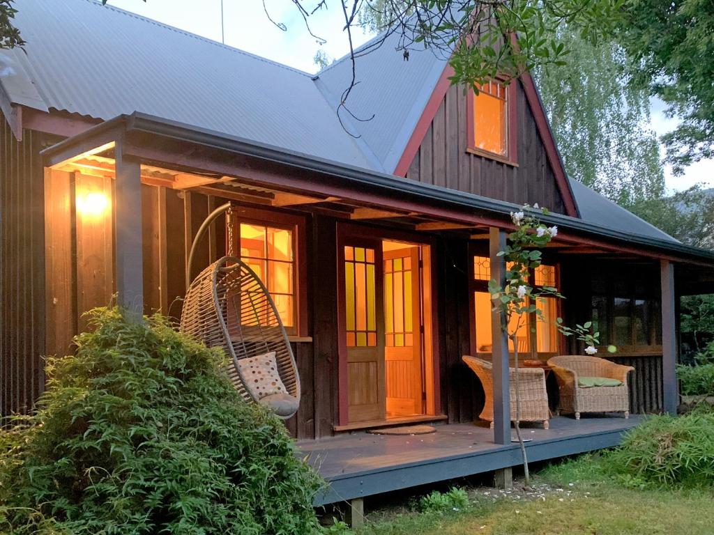 een tiny house met een veranda en rieten stoelen bij Quail Farm, Colonial charm in Nelson