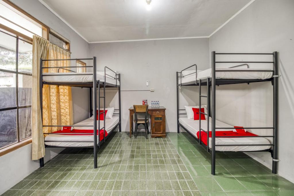 Cette chambre comprend 3 lits superposés et un bureau. dans l'établissement RedDoorz Hostel near Adisucipto Airport Yogyakarta, à Yogyakarta