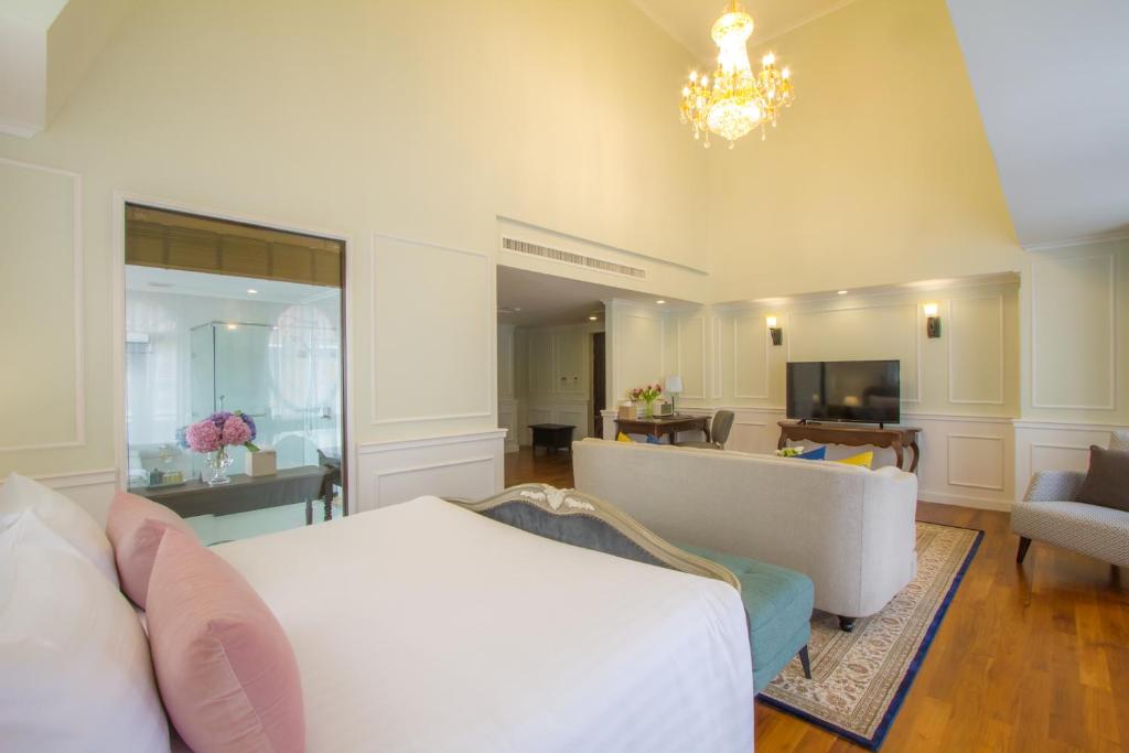 A large open-plan room with a bed, sofa, television area and glass-partitioned bathroom.