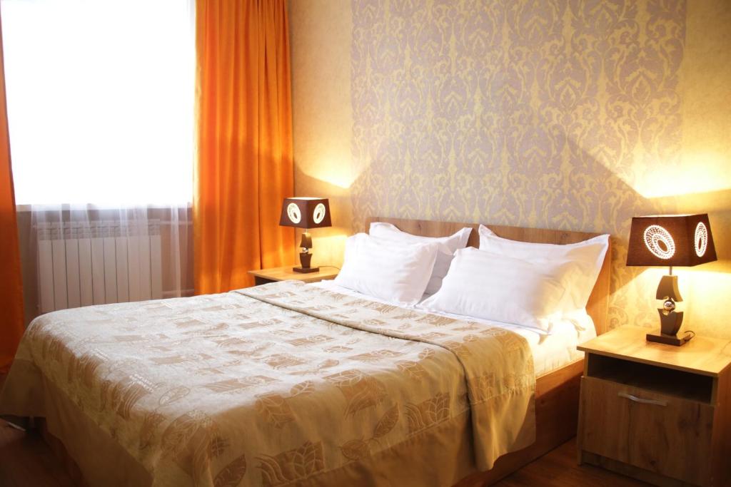 um quarto com uma cama com 2 candeeiros nas mesas em City Hotel em Öskemen