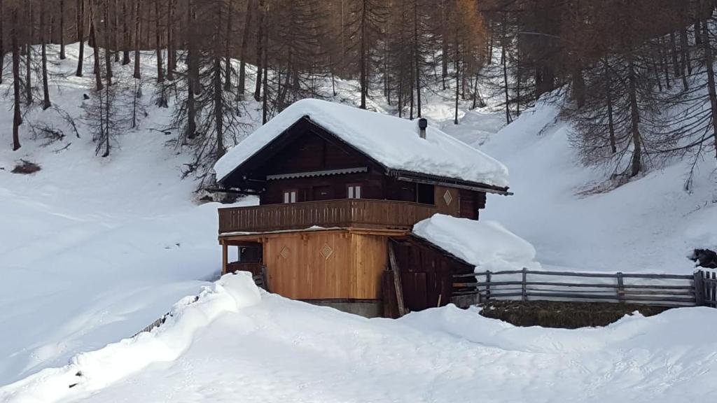 a small cabin covered in snow with a fence at Ferienhütte Ortnerkasa in Heiligenblut