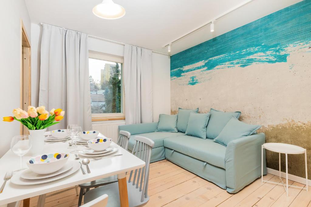 a living room with a table and a blue couch at Seaside Apartment Kraszewskiego by the Beach in Sopot by Renters in Sopot