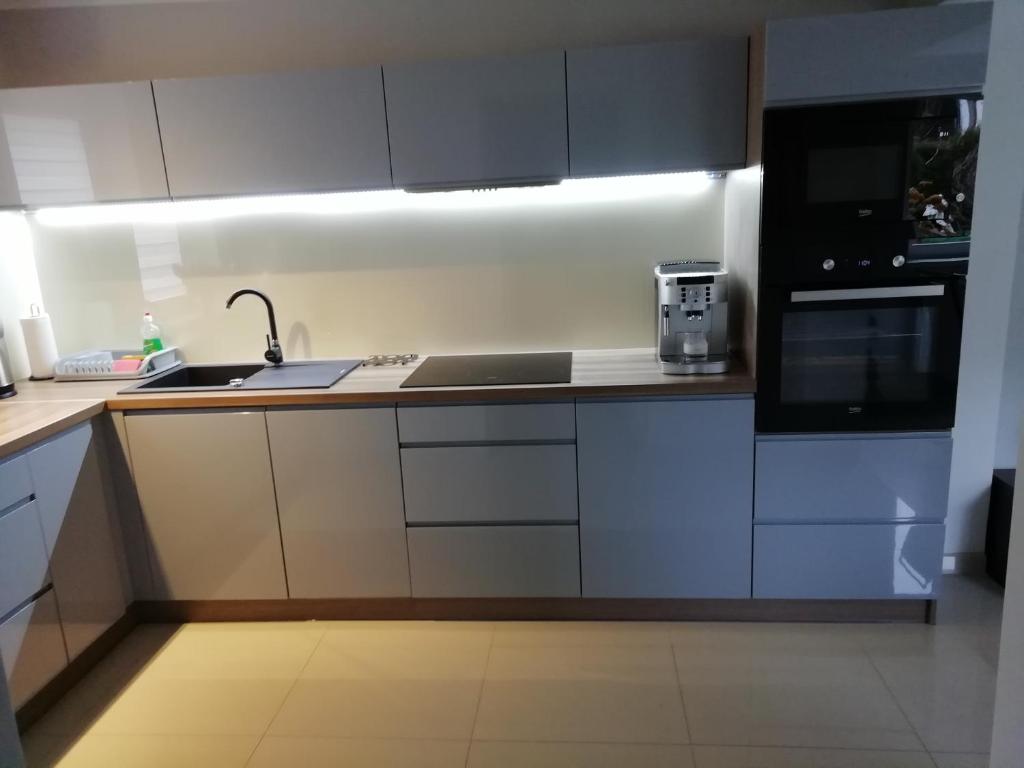 a kitchen with white cabinets and a sink and a microwave at APARTAMENT WŁODEK in Jelenia Góra