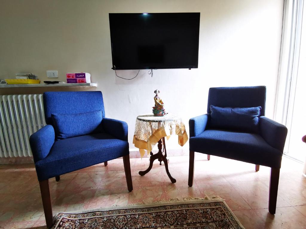 2 Stühle und ein Tisch im Wohnzimmer mit einem TV in der Unterkunft Berdawny Apartments in Zahlé