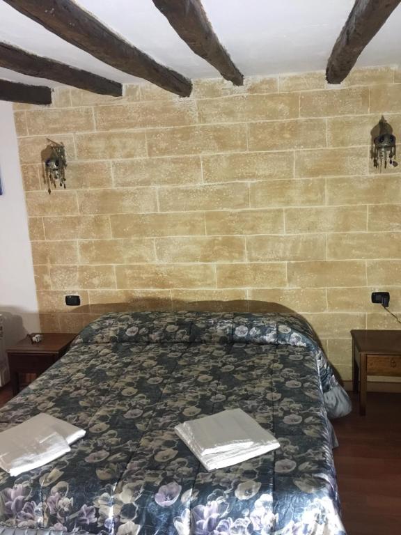 パレルモにあるApartment Bellomiaのレンガの壁、ベッド付きのベッドルーム1室