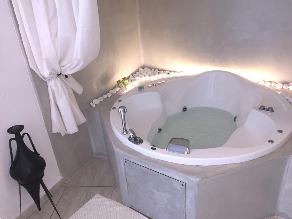 a large white tub in a bathroom with a curtain at Aeolos Art & Eco Suites Adults Only in Imerovigli