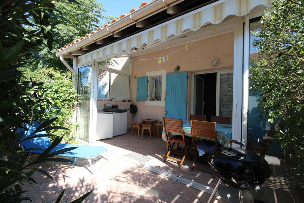 un patio avec une cuisine, une table et des chaises dans l'établissement Belle villa 4 -5 couchages 2 chambres terrasse piscine commune parking dans résidence sécurisée 300m de la mer LRMA82, à Portiragnes