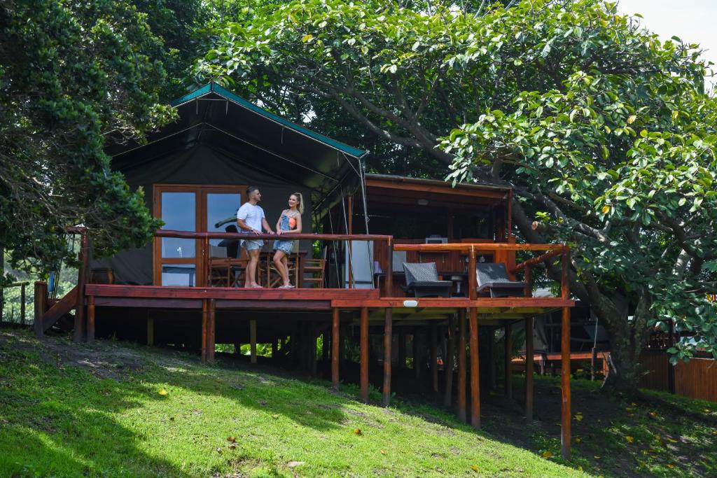 two women sitting on the deck of a tree house at Kingfisher Lakeside Retreat in Trafalgar