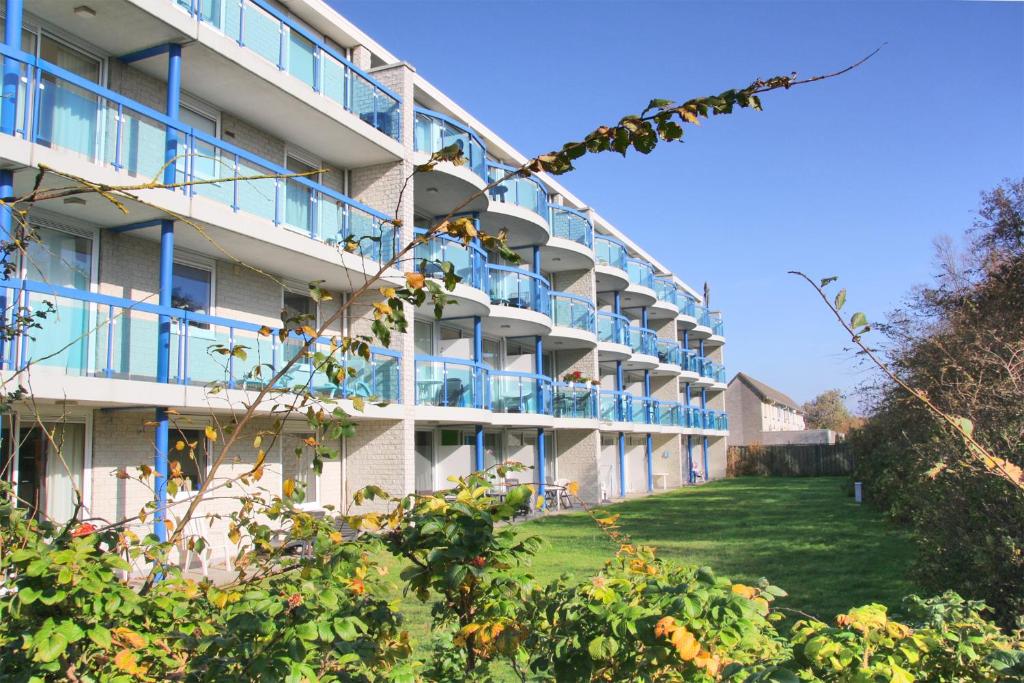 ein Apartmenthaus mit blauen Balkonen und einem Hof in der Unterkunft Appartement 19 Callantsoog in Callantsoog