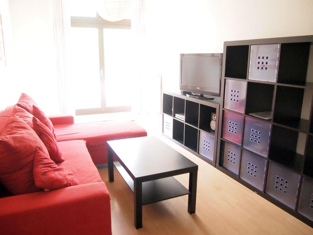 salon z czerwoną kanapą i telewizorem w obiekcie Apartements im TSB Sportpark w mieście Weil am Rhein