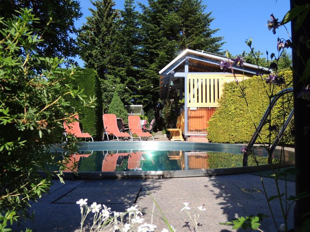 a pool with chairs and a house in the background at Pension 19 in Pirna
