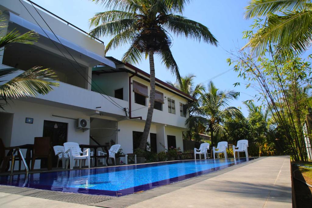 a villa with a swimming pool and palm trees at Optimum Residencies in Negombo