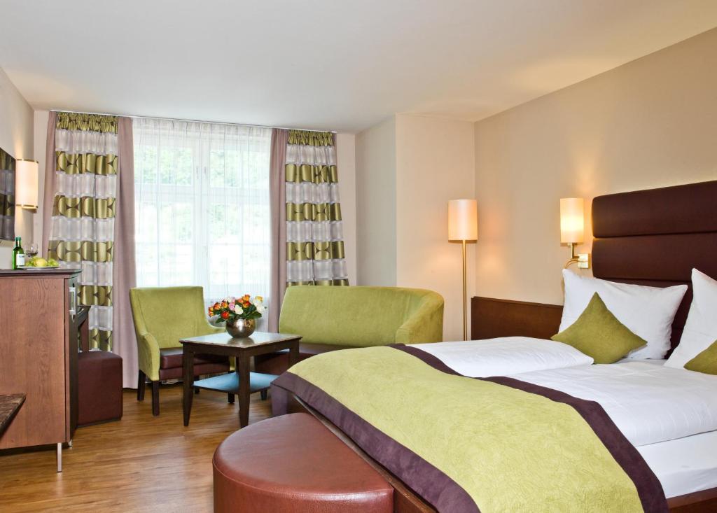 パッサウにあるホテル ケーニッヒのベッド1台と椅子2脚が備わるホテルルームです。