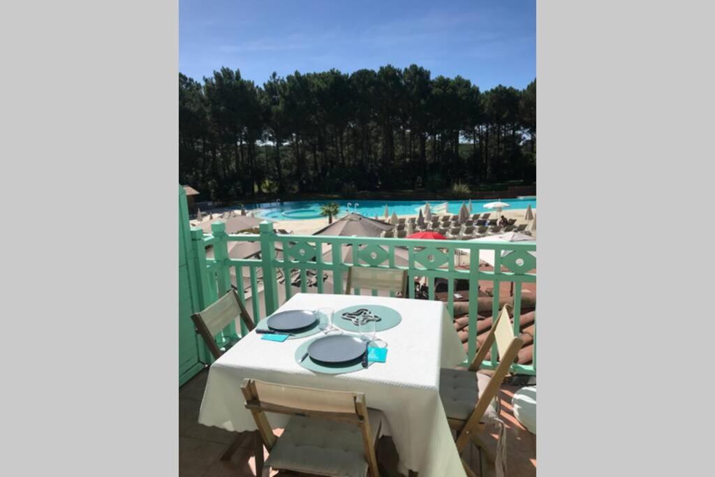 a table and chairs on a balcony with a pool at Lumineux, vue piscine, face au Golf, Lacanau Ocean in Lacanau
