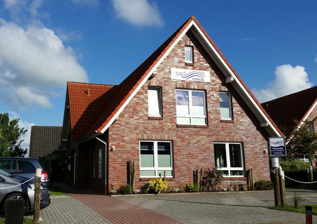 a brick house with a car parked in front of it at Pension Blaue Nordseewelle in Neuharlingersiel