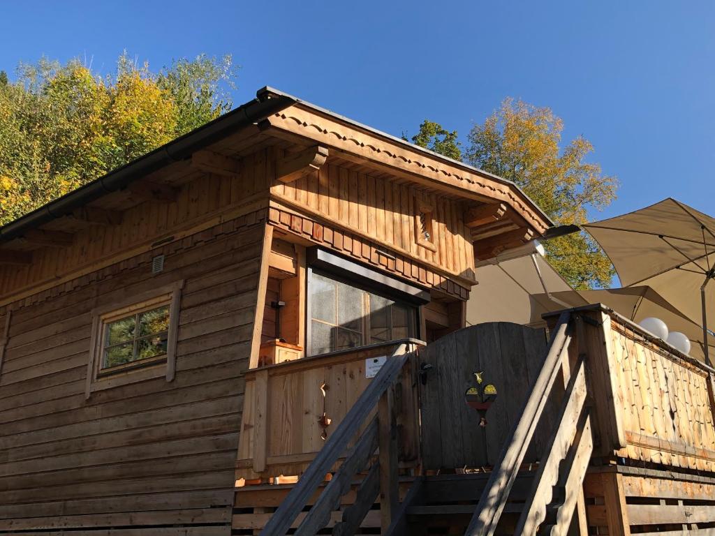 a wooden cabin with a large window and an umbrella at Chalet - Direkt am 5 Sterne Campingplatz Aufenfeld im Zillertal mit Hallenbad und Sauna in Aschau