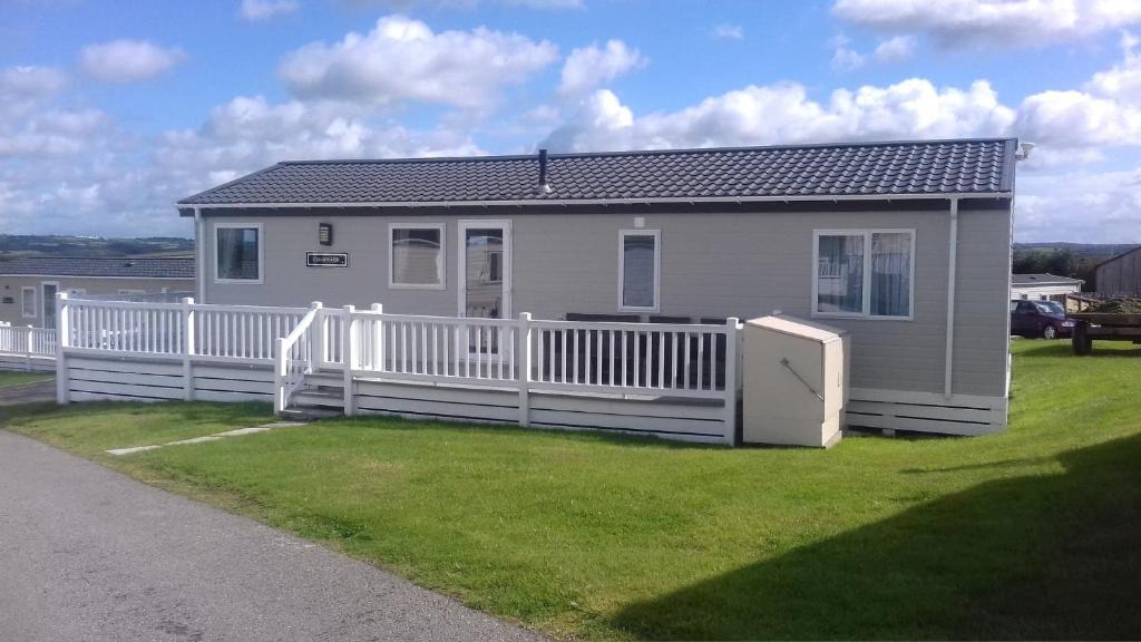 a small house with a white fence in a yard at Clearwater lodge Widemouth sands in Poundstock