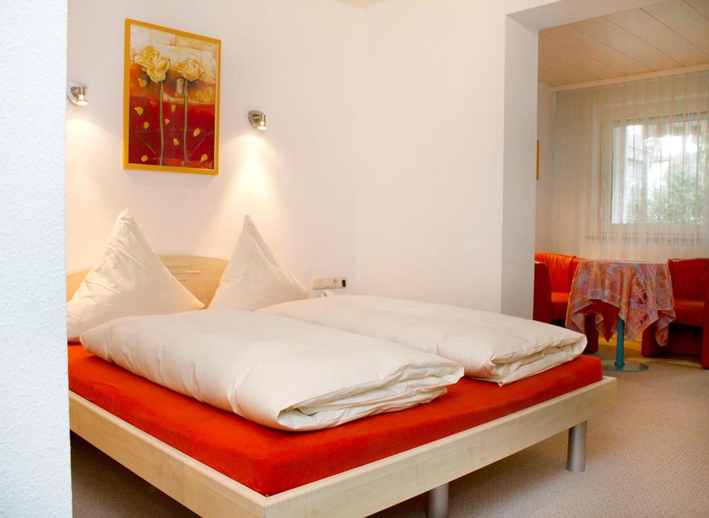 a bedroom with a bed with white sheets and a red blanket at Best Breakfast - Hotel Justina in Bad Wörishofen