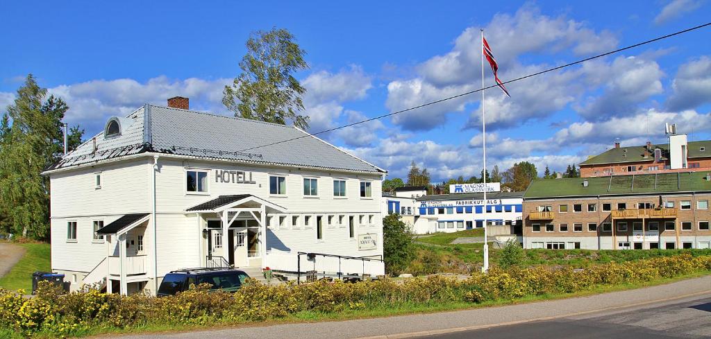 a white house with a flag on the side of a street at Hotell Magnor Bad in Magnor