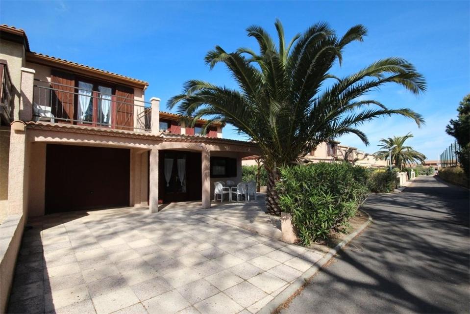 une maison avec un palmier devant dans l'établissement Domaine de vacances à 600m de la plage villa d'angle, climatisée, grande terrasse 3 chambres 7 couchages WIFI animations et piscines en supplément LRPDSO7, à Portiragnes