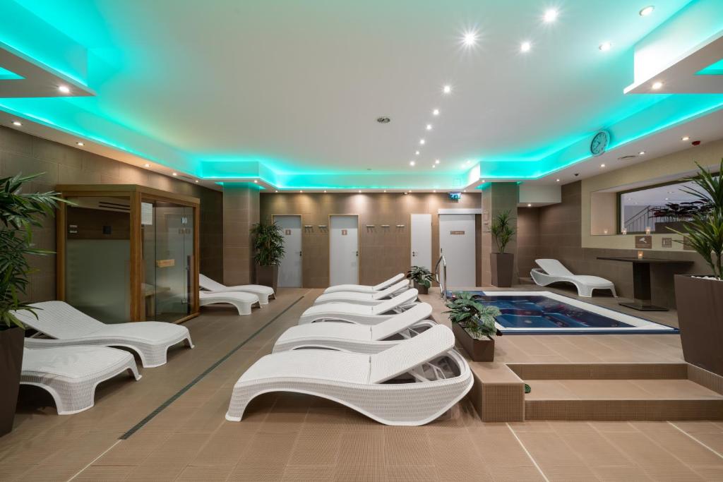a hospital lobby with white chairs and a pool at Bükkös Hotel & Spa in Szentendre