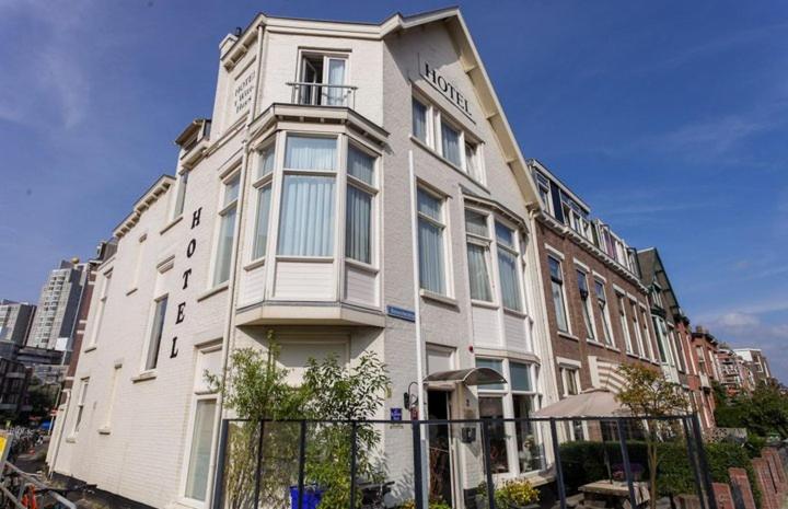 un grand bâtiment blanc avec une clôture devant lui dans l'établissement Hotel 't Witte Huys Scheveningen, à Scheveningen