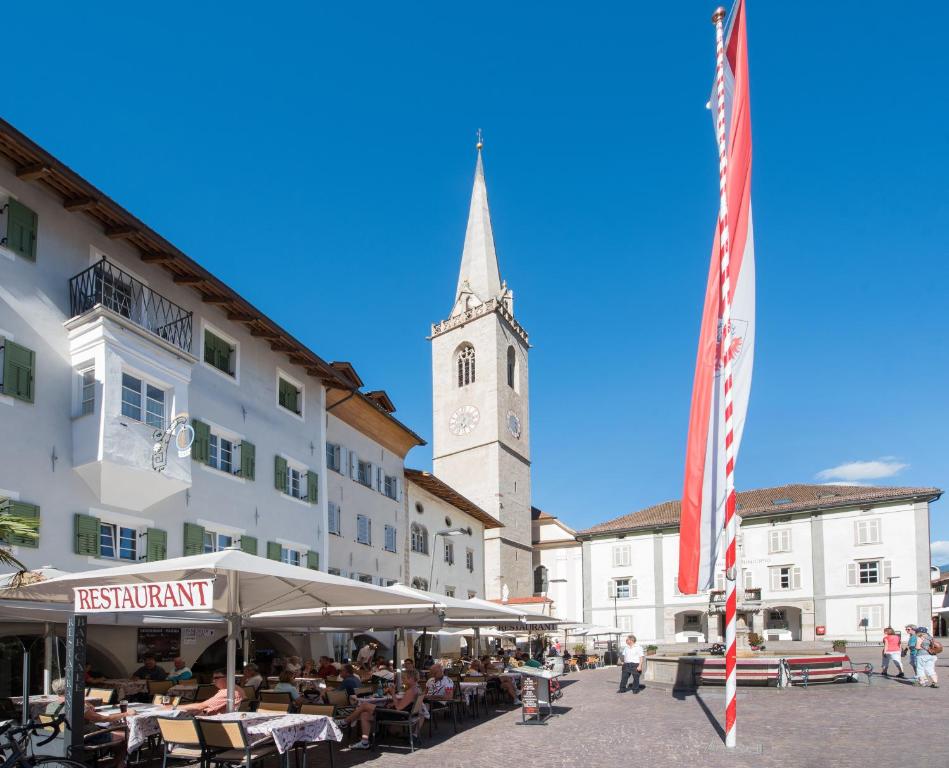 a town square with a clock tower with a flag at Gasthof Mondschein in Caldaro