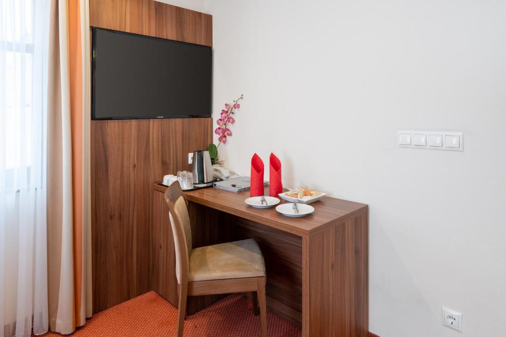 a room with a desk with a chair and a television at Bükkös Hotel & Spa in Szentendre