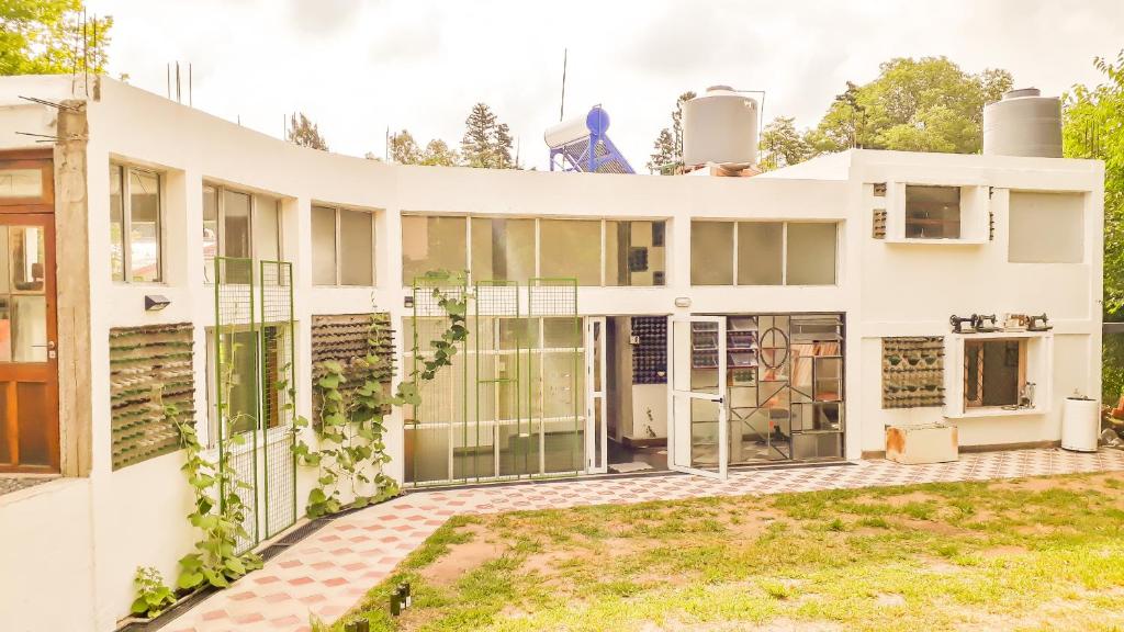 a house with a lot of windows at Hostel Casa de artistas Multiespacio Tanti in Tanti