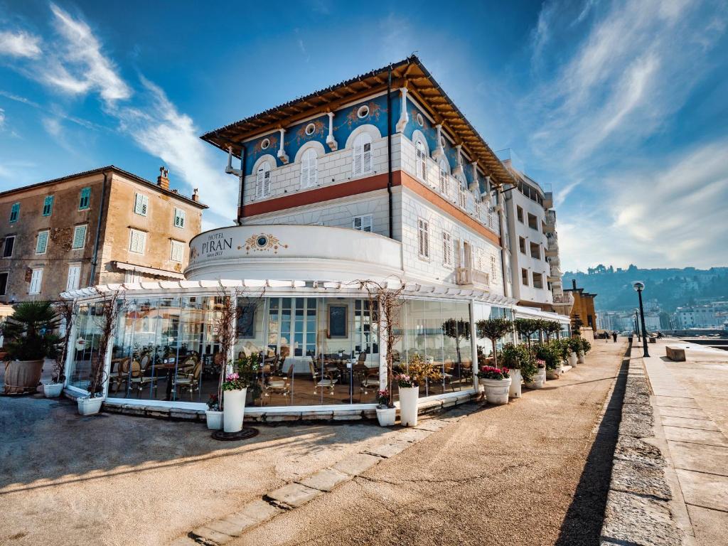 a building with windows and plants on a street at Hotel Piran in Piran