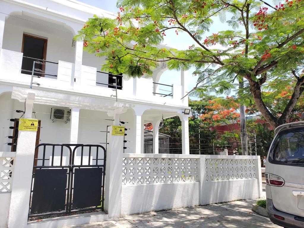 une maison blanche avec une clôture blanche et un arbre dans l'établissement SATRANA HOTEL TAMATAVE, à Toamasina
