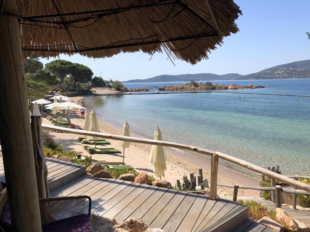 widok na plażę z parasolami i ocean w obiekcie Grand Hôtel De Cala Rossa & Spa Nucca w mieście Porto-Vecchio