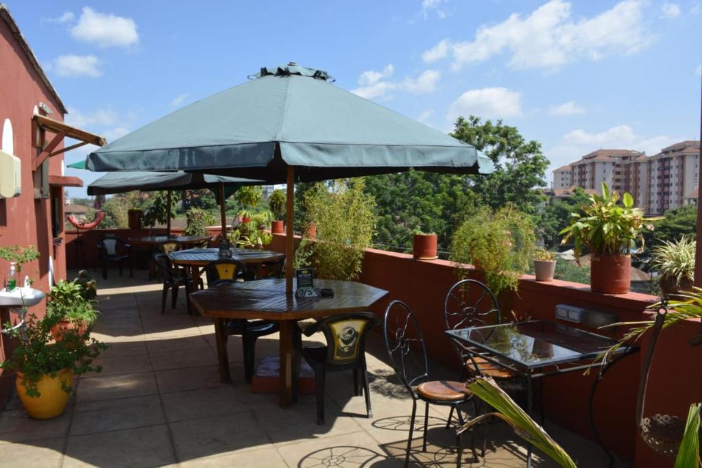 un patio con mesas, sillas y una sombrilla en Khweza Bed and Breakfast en Nairobi