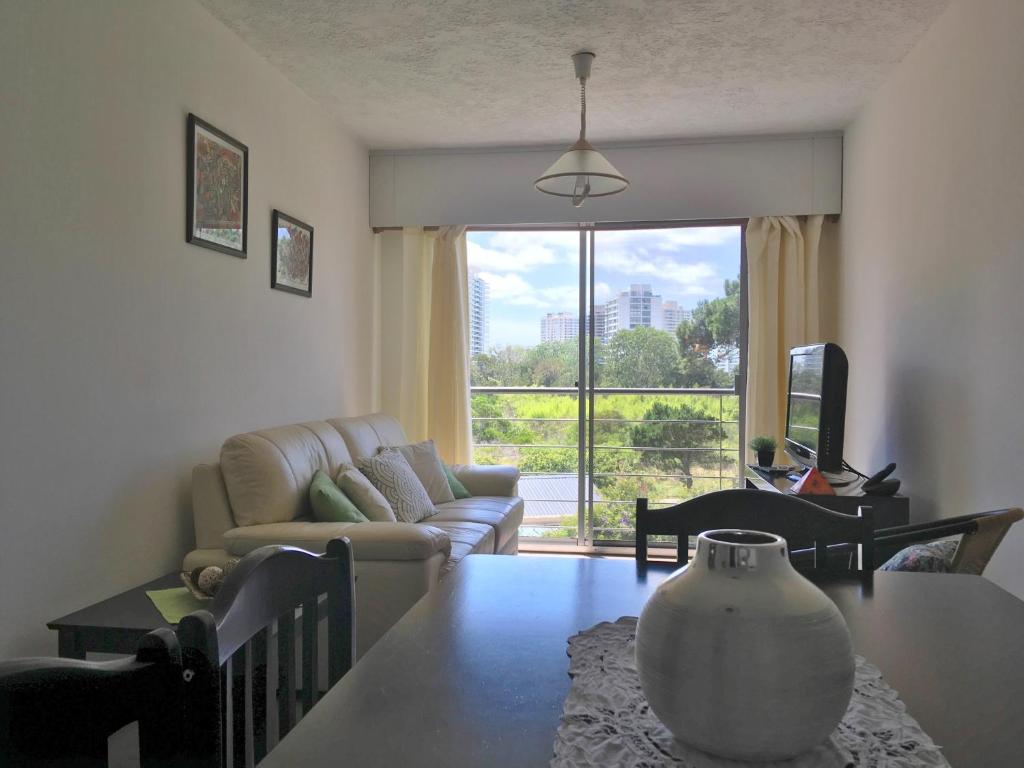 ein Wohnzimmer mit einem Sofa und einem Tisch mit einer Vase in der Unterkunft Punta del Este Aidy Grill in Punta del Este