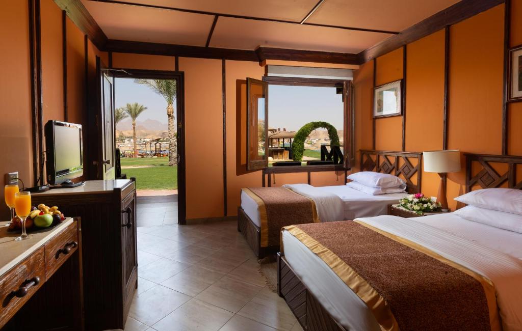 a hotel room with two beds and a television at Xperience Golden Sandy Beach in Sharm El Sheikh