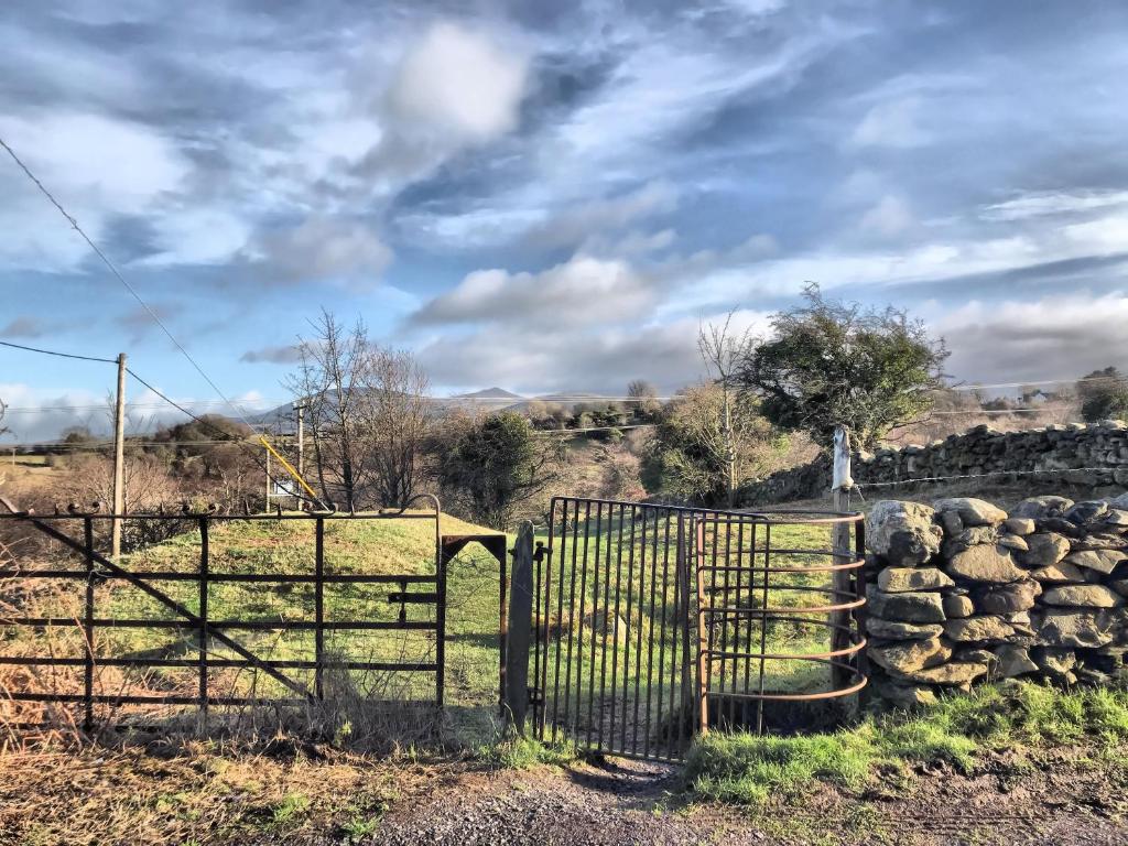 a gate in a field with a pile of rocks at Pili Pala Cottage, outstanding views and minutes to Zip World in Tregarth