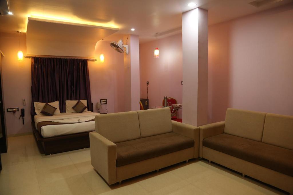 a bedroom with a bed and a couch and a chair at Hotel Sai Guest House in Nagpur