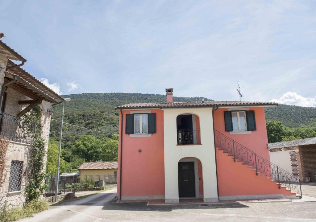 una pequeña casa naranja y blanca con una escalera en Alloggio vocabolo San Sebastiano, en Massa Martana