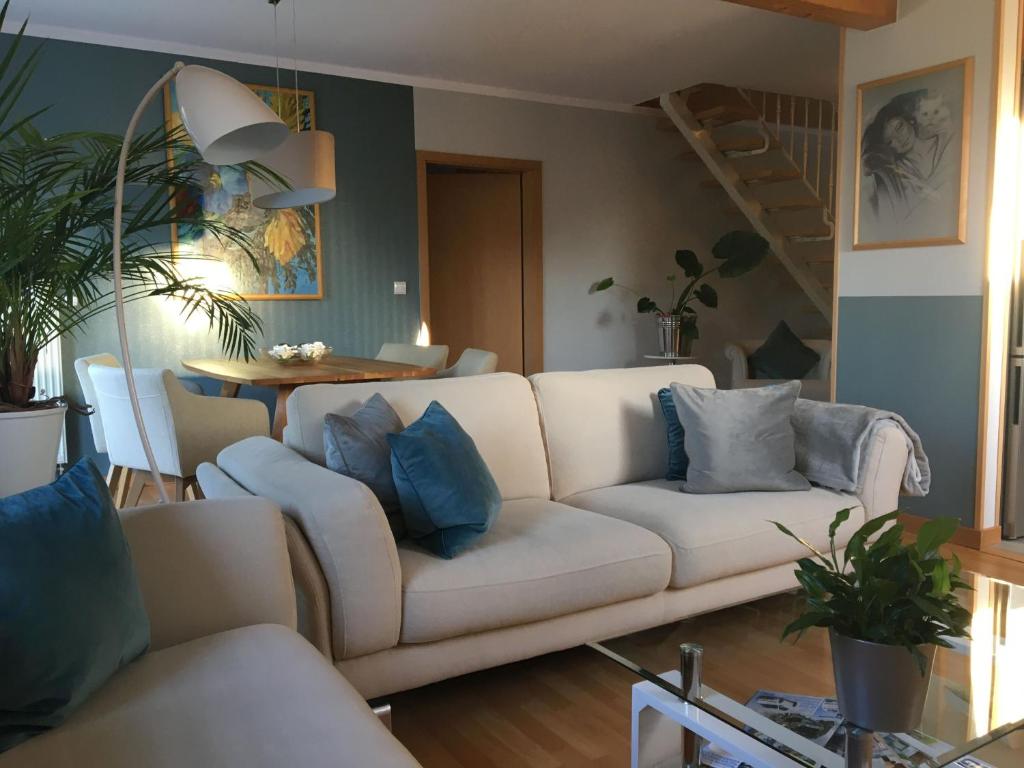 ein Wohnzimmer mit einem weißen Sofa und blauen Kissen in der Unterkunft Ferienwohnung zur Himmelsscheibe new Art in Ziegelroda