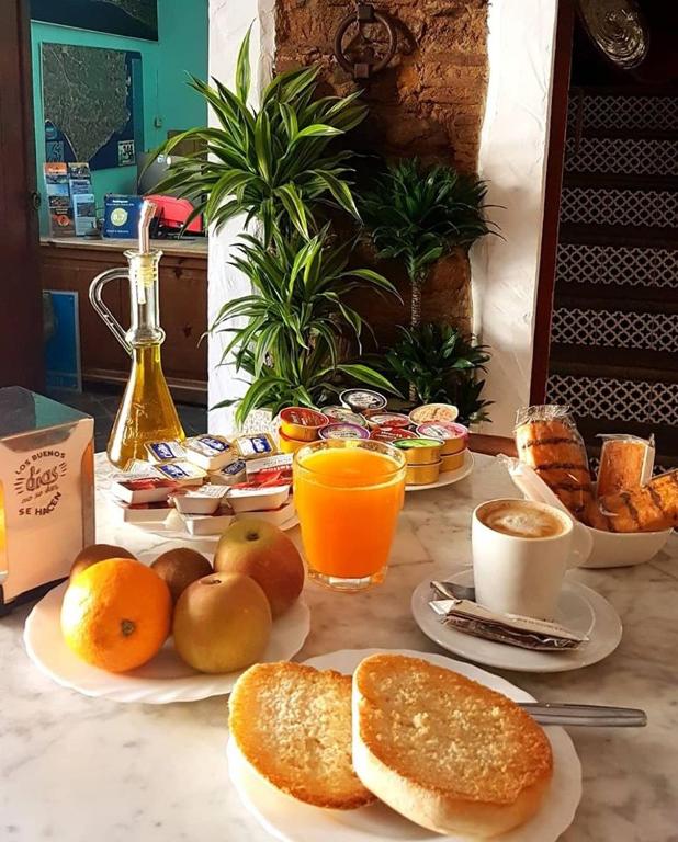 a breakfast table with bread and fruit and orange juice at Hostal El Asturiano in Tarifa