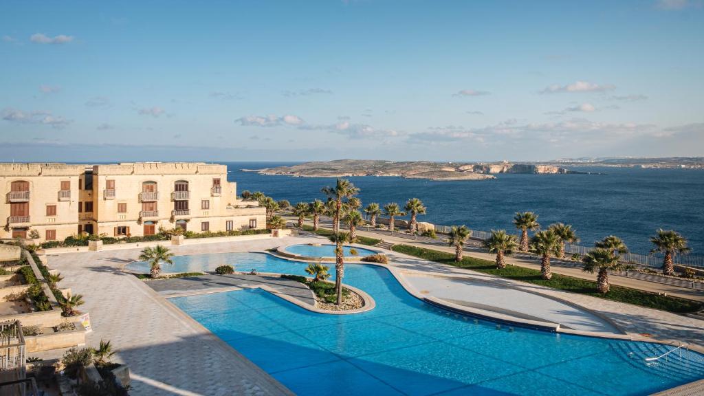 a view of a resort with a swimming pool and the ocean at Cosy apartment in Historic Fort Chambray, Gozo in Mġarr