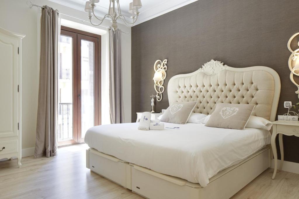 - une chambre avec un grand lit blanc et une tête de lit blanche dans l'établissement Kursaal - Basque Stay, à Saint-Sébastien