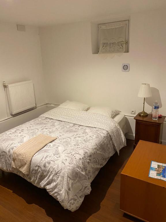 um quarto com uma cama e uma mesa com um candeeiro em Lalanie em Savigny-sur-Orge